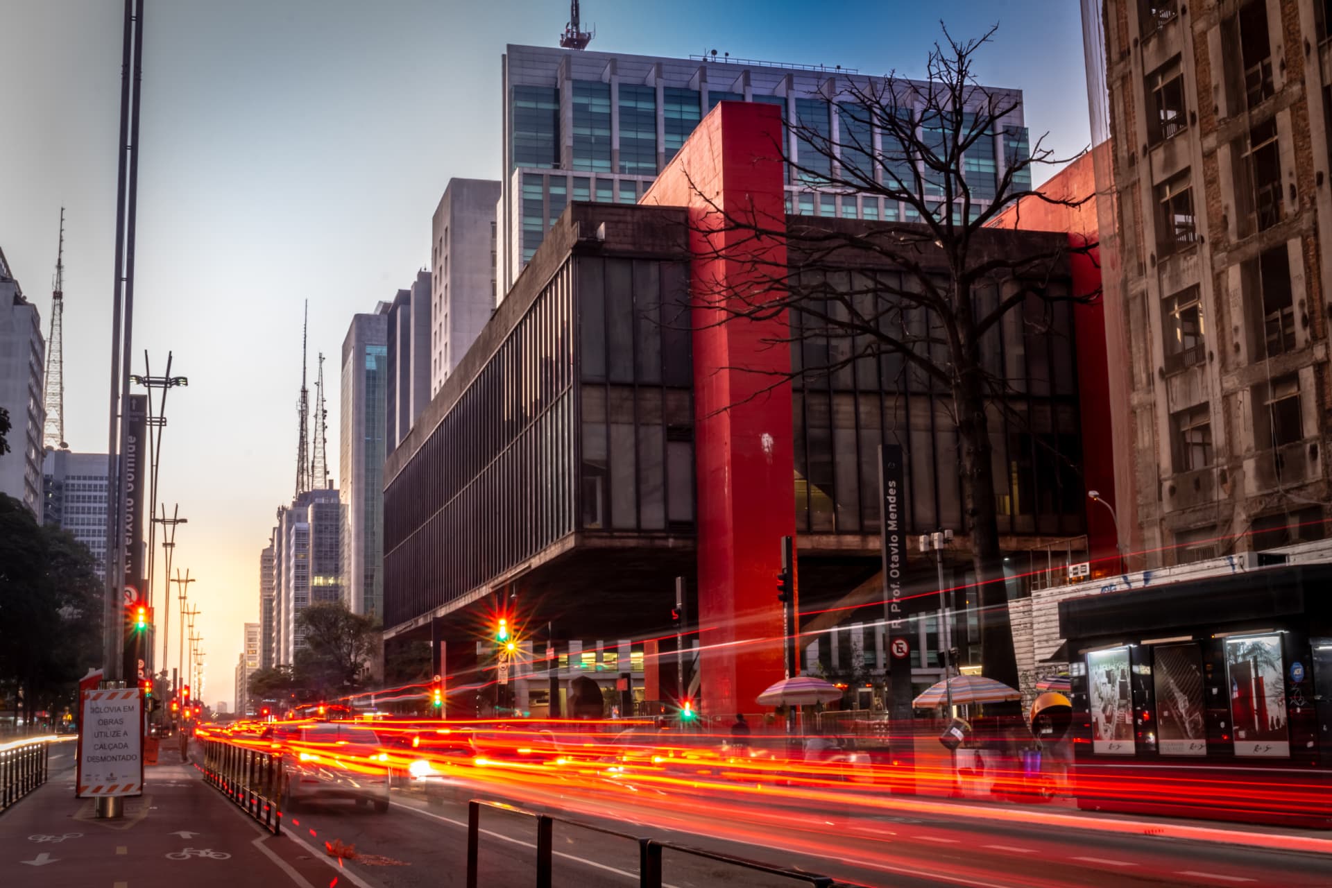 The São Paulo Museum of Art on Paulista Avenue at dusk, with traffic light trails crossing the avenue