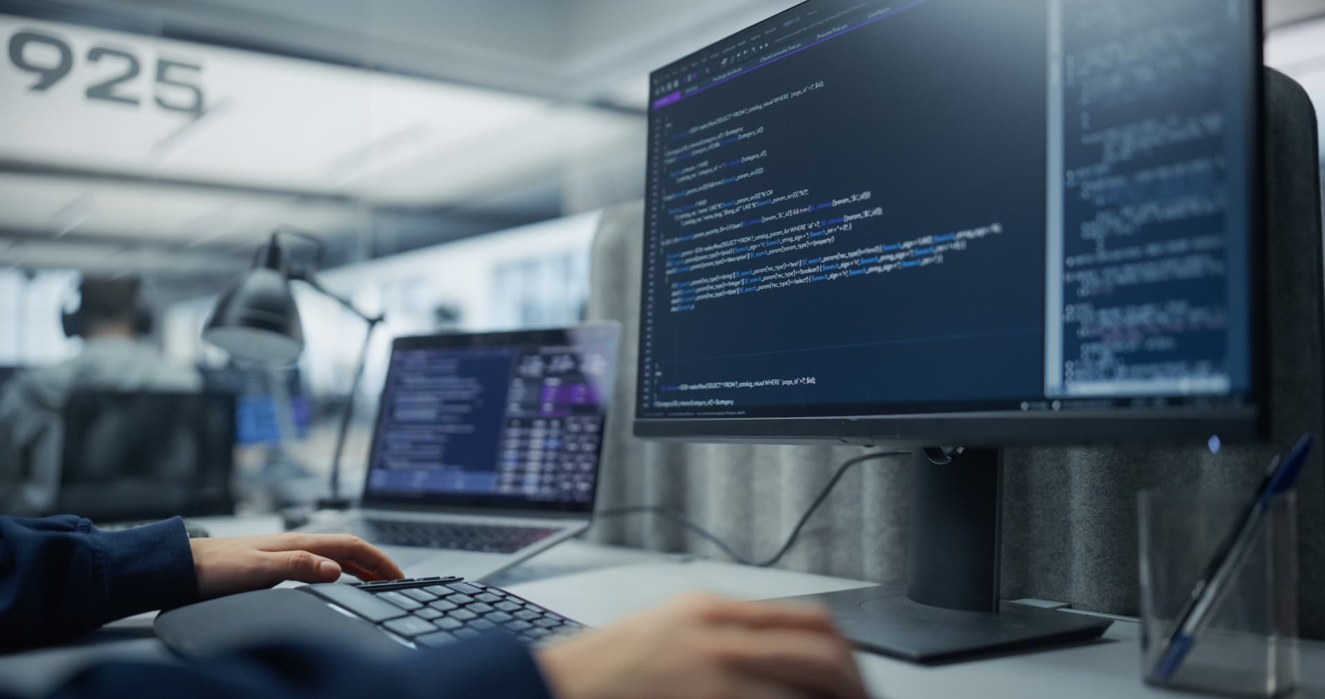 Developer working at a desk with several monitors showing code